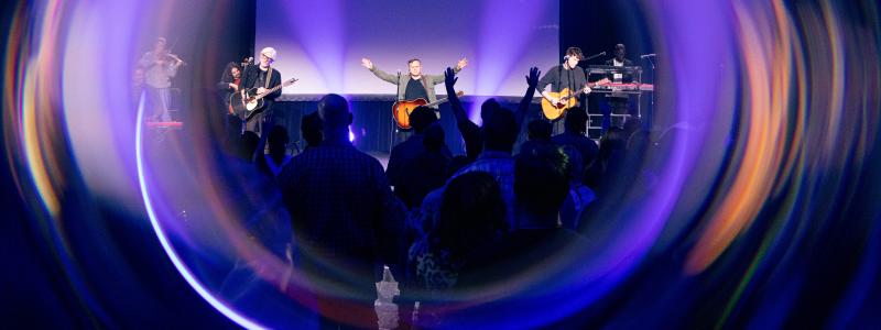 Concert with vibrant lights and audience, musicians performing on stage.