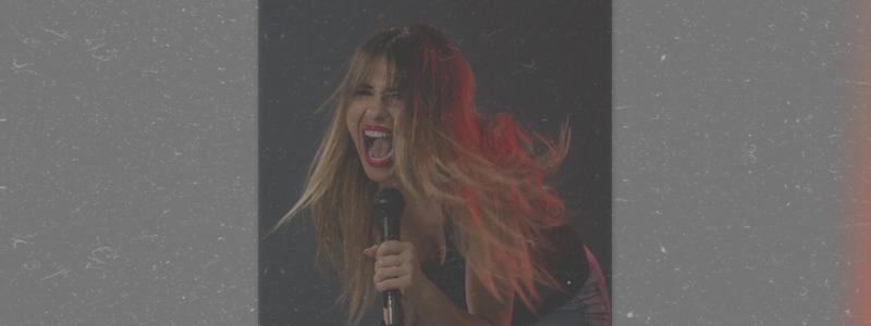 Singer passionately performing on stage with a microphone, hair loose, dynamic lighting.