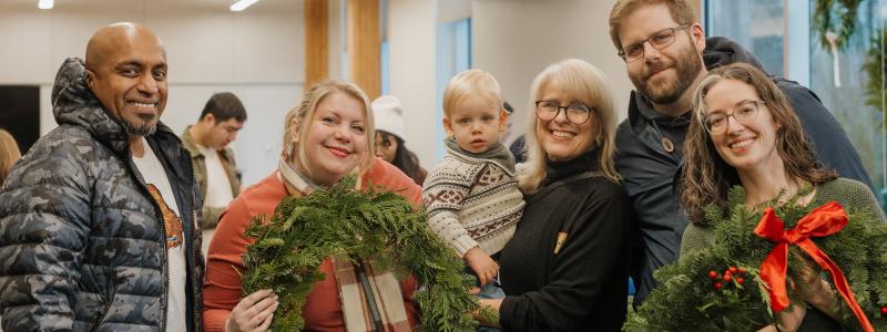 A family pose and smile at the camera, holding wreaths.