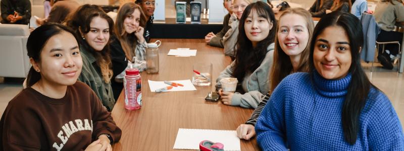 People smiling and sitting at a table in the Global Lounge