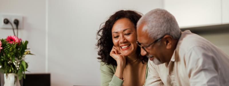 Couple smiling looking at a laptop together