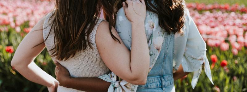 Two women embracing each other in a field of flowers.
