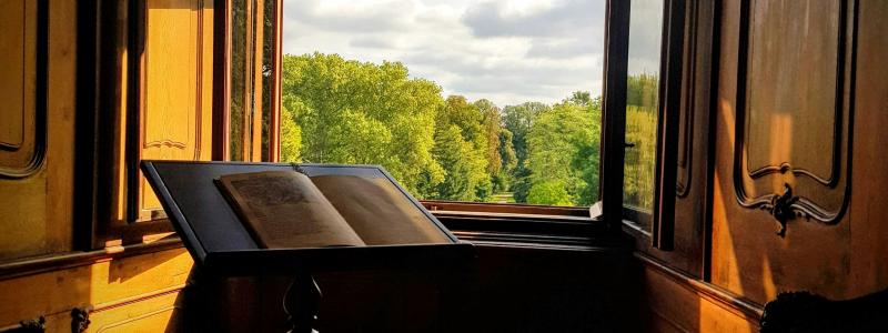 stock photo of book on stand in front of an open window in a grand room