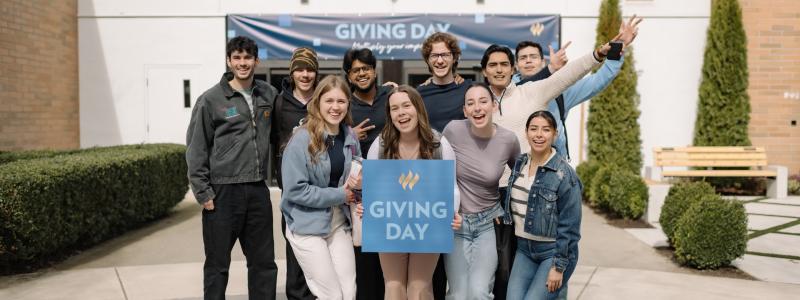 Students standing in front of Reimer Student Centre with Giving Day sign