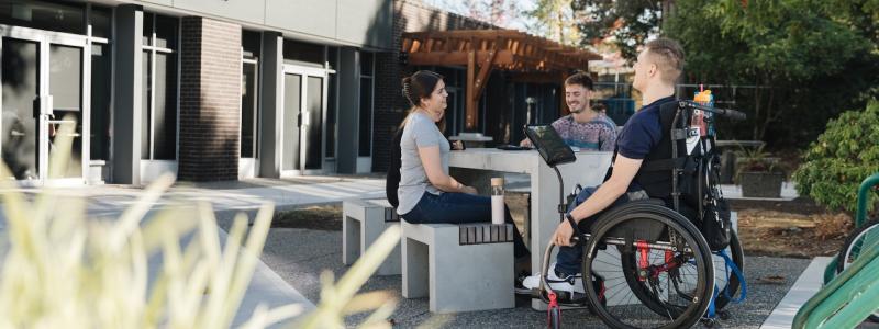 group of people at picnic table in front of DeVries Centre