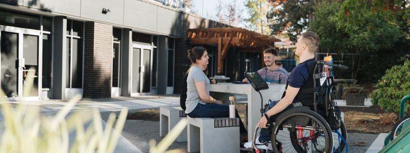 group of people at picnic table in front of DeVries Centre