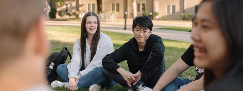 group of students sitting outside on the grass