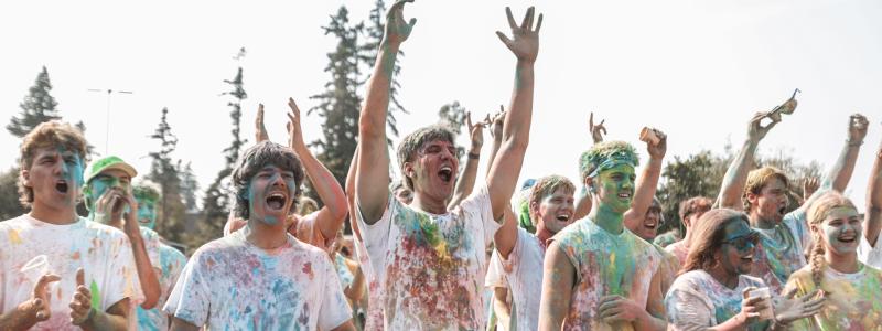 group of people covered with coloured chalk cheering
