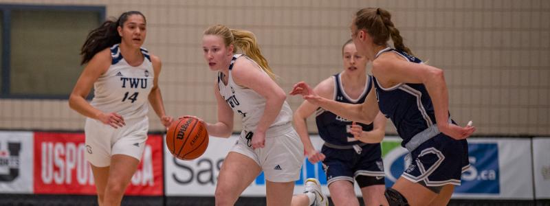 Girls in white and blue jerseys playing basketball.