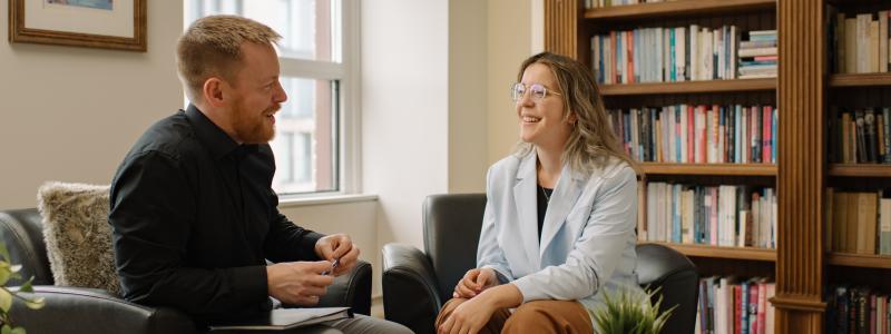 Two people in conversation in a book-lined room at TWU’s Laurentian Leadership Centre in Ottawa.