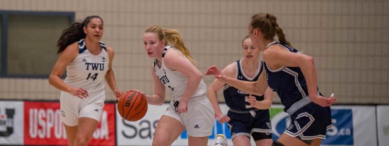 Girls in white and blue jerseys playing basketball.