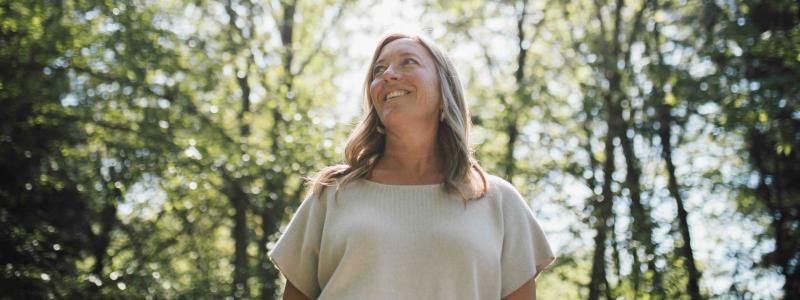 Sara Kraushar smiling outdoors beneath sunlit trees.