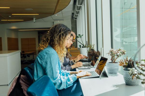 Three students sitting side-by-side studying on their computers