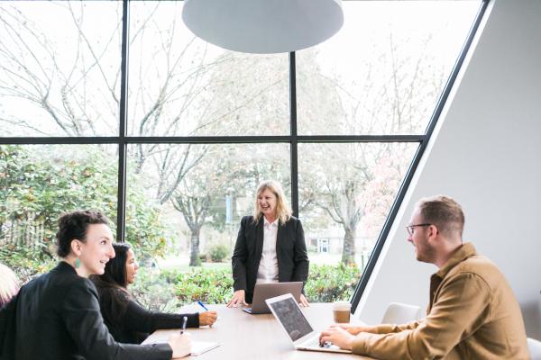 Group of people sitting at a table talking to one woman standing