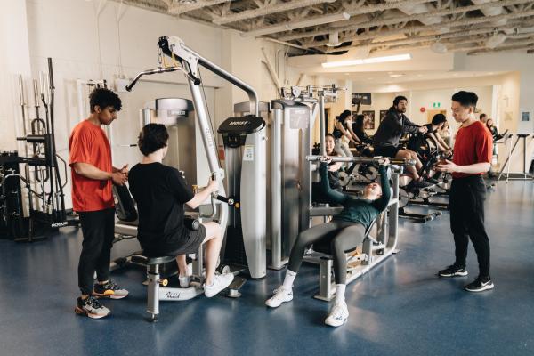 Students using strength-training equipment in a university fitness centre.