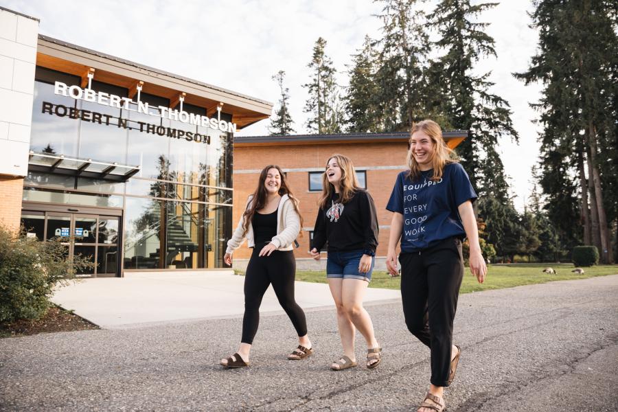 Three students happily walking past Robert N. Thompson