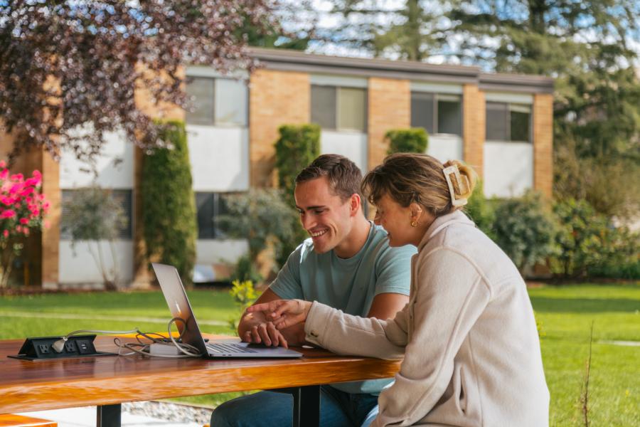 Students looking at laptop outdoors