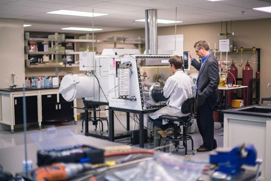 Research lab with student using a machine and professor instructing