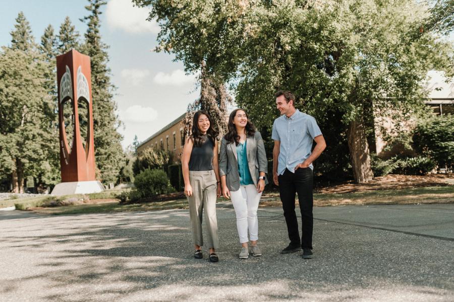 Three students standing by bell tower