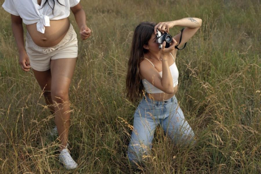 Girl kneeling on the grass taking a photo with her camera