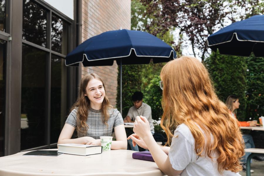 women talking outside at table