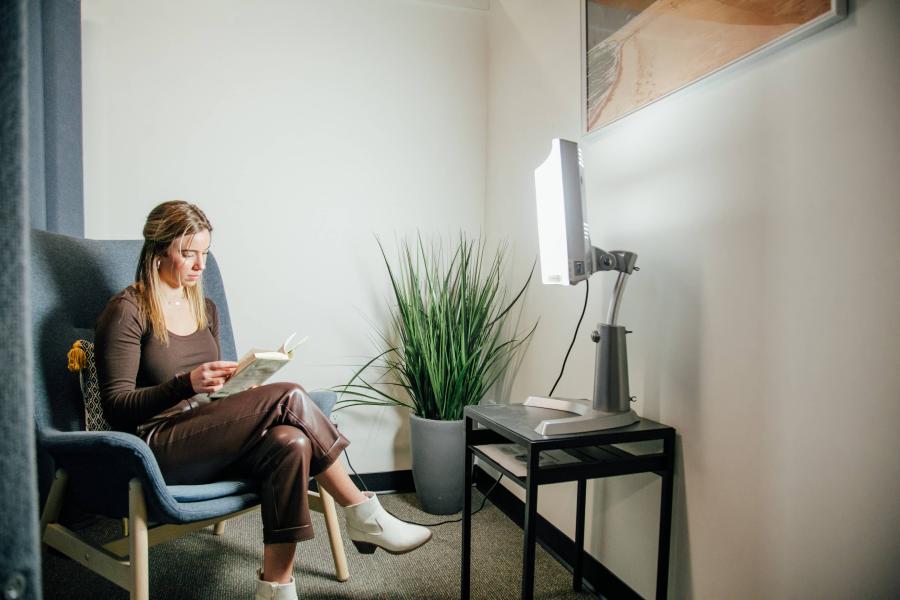 young woman reading a book in front of sunlight lamp