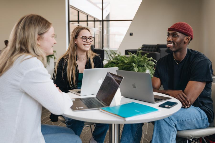 three students enjoying their conversation at a table