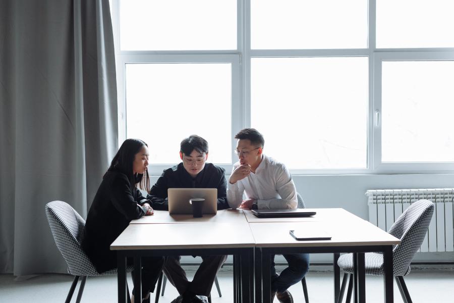 three students working on a laptop