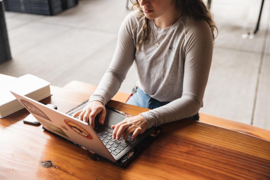 woman using laptop outdoors on wooden table