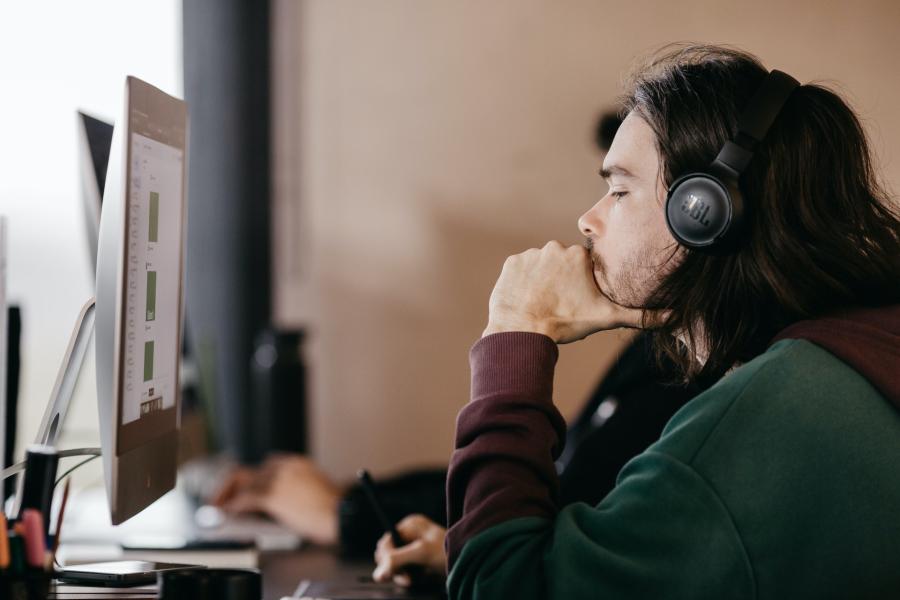 man concentrating will wearing headphones and working on a computer