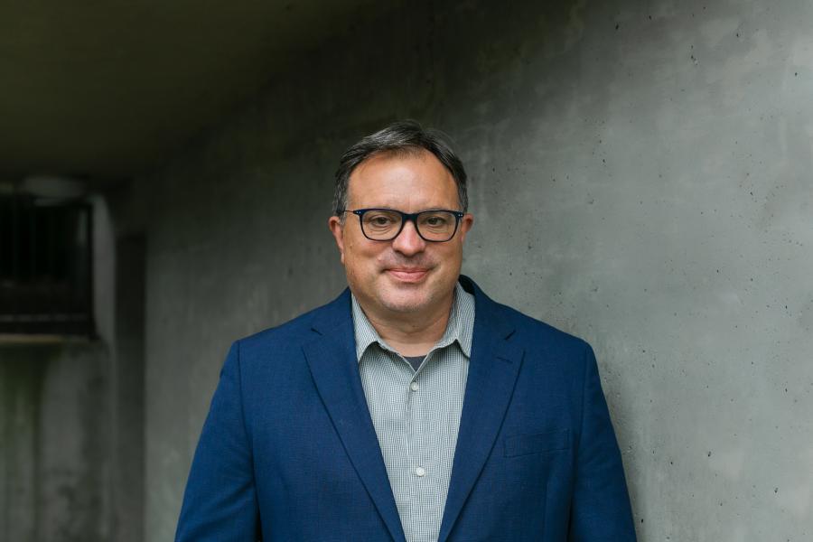 Scott Macklin standing in front of grey wall