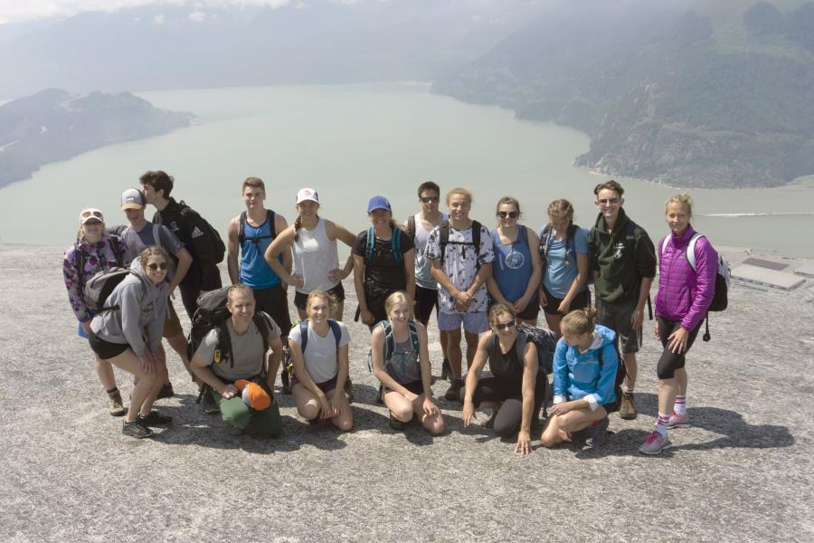 group of people standing on a rock in front of a river