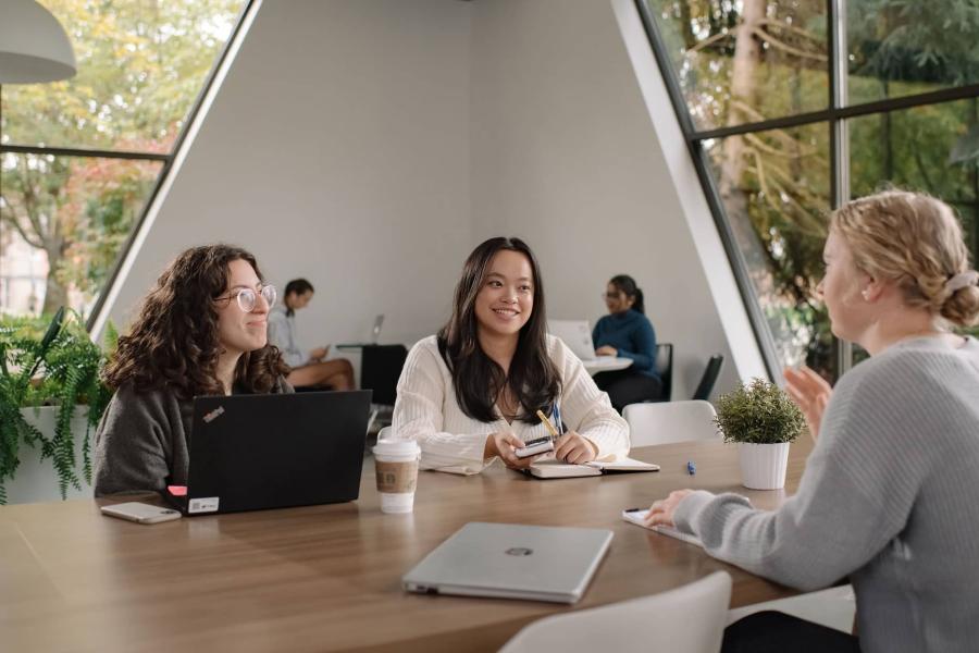 Three women sitting at a table in Trinity Commons talking to each other
