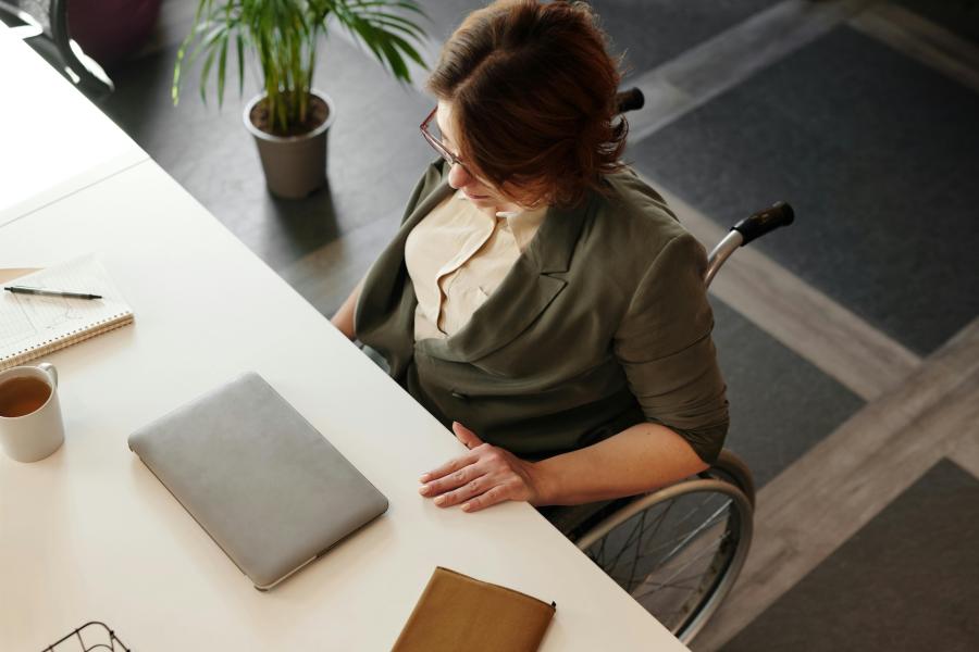 person in wheelchair at desk with laptop