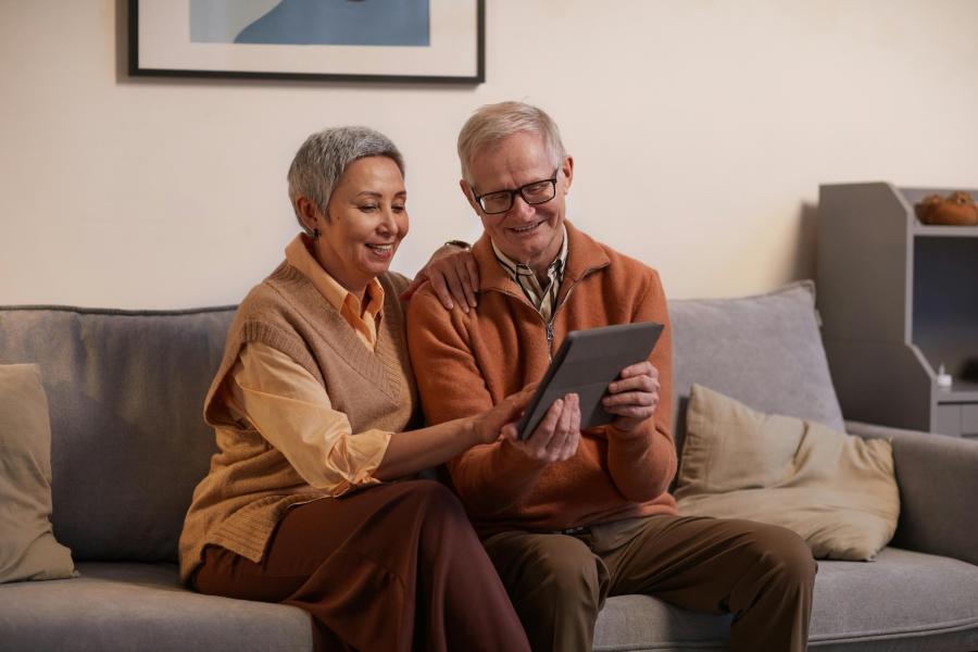 seniors looking at ipad together on couch