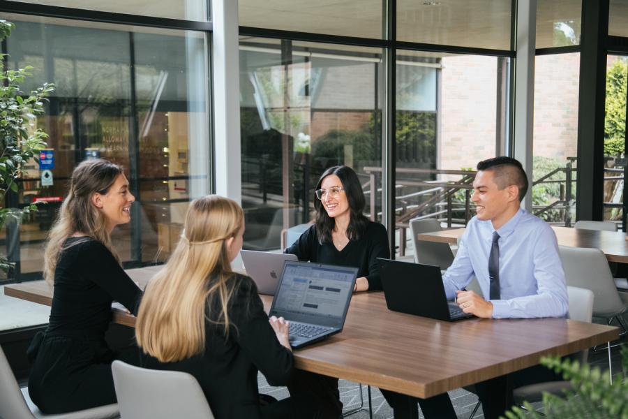 Four people sitting at a desk working or talking