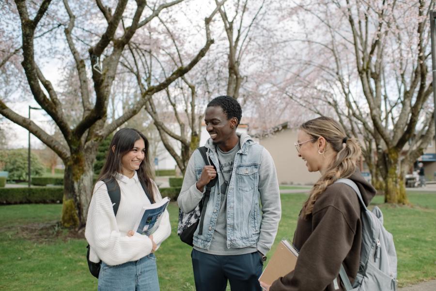students standing outside with backpacks and books, talking