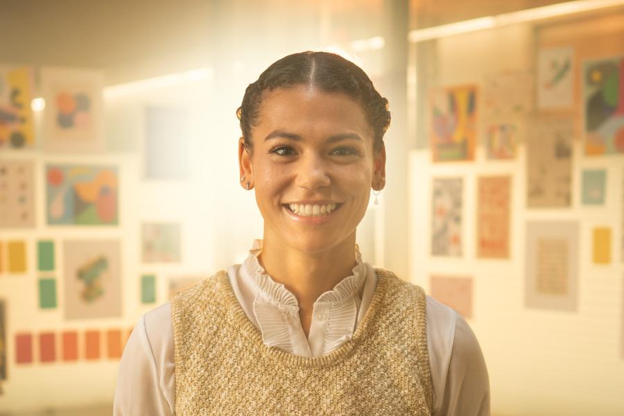 Aliya smiling at the camera and standing in front of some light