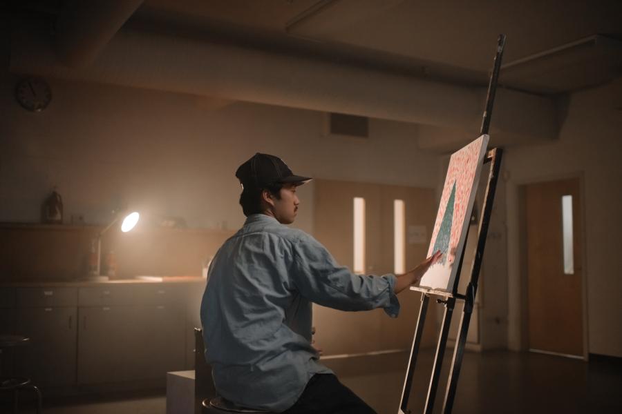 A student painting in a dimly lit room