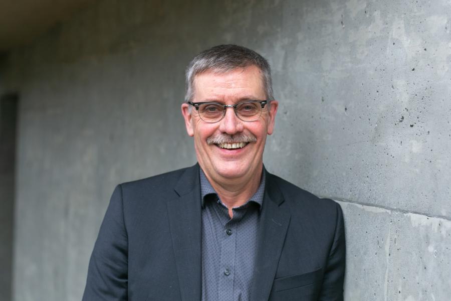 Bob Wood standing in front of grey wall smiling