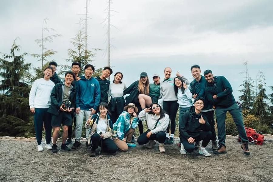 Group of people smiling on a cloudy day in a forest setting.