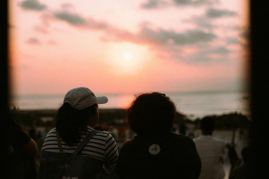 Two people watch a sunset over the ocean.