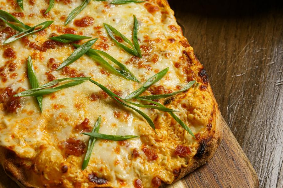 Flatbread pizza with cheese and green onions, beside sliced cucumbers.