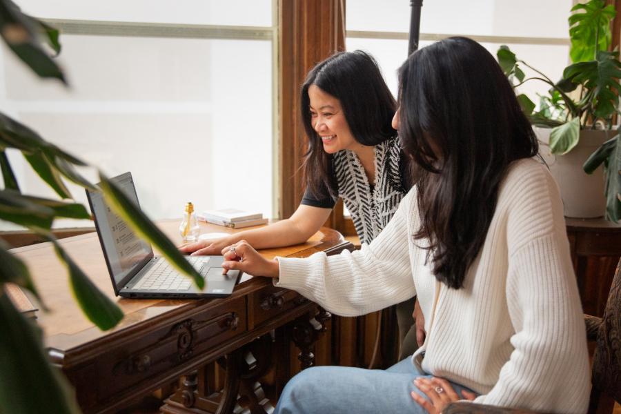 people looking at a laptop on a desk together