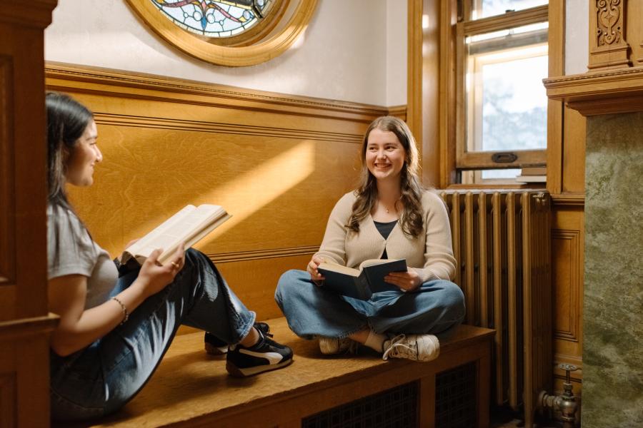 Two students studying together in a relaxed campus setting.