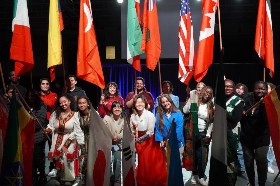 Students hold international flags during an Intercultural Programs event celebrating cultural diversity and global community.