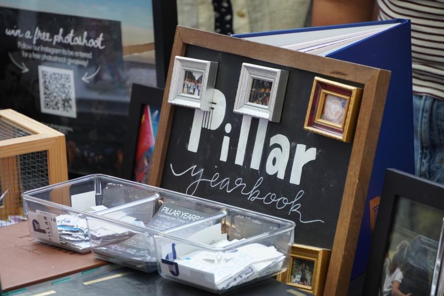 A Student Media information table features the Pillar yearbook, sample photos, promotional materials, and a contest display, highlighting opportunities for students to connect with campus publications and storytelling initiatives.
