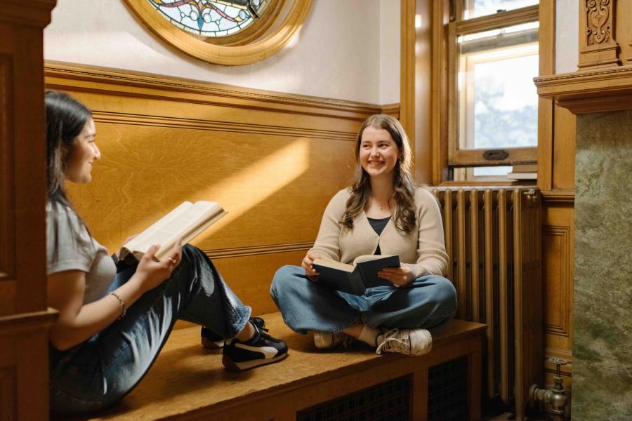 Two students studying together in a relaxed campus setting.