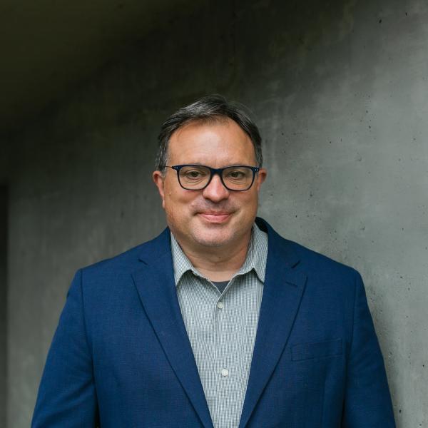 Scott Macklin standing in front of grey wall