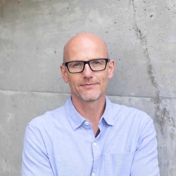 Myron Penner headshot standing in front of grey wall